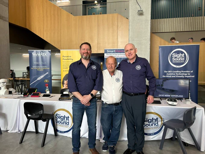 Graeme, Tony and Stuart stand on front of the Sight and Sound Technology stand. 