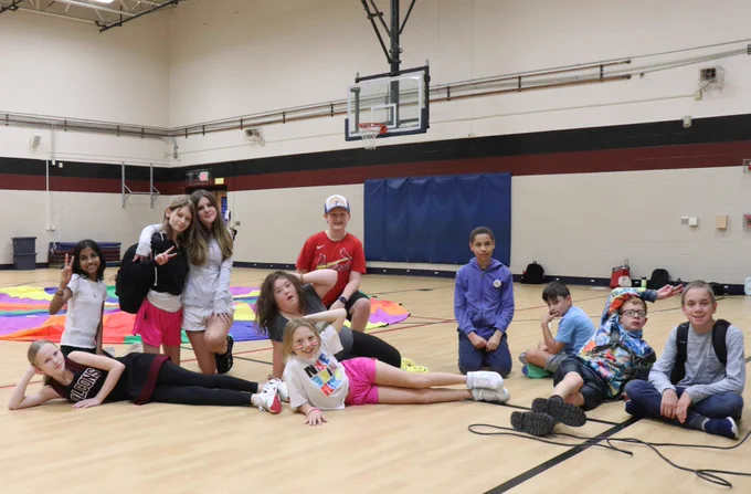 A group of 11 Rockwood students smile after PE class in a school gymnasium. 