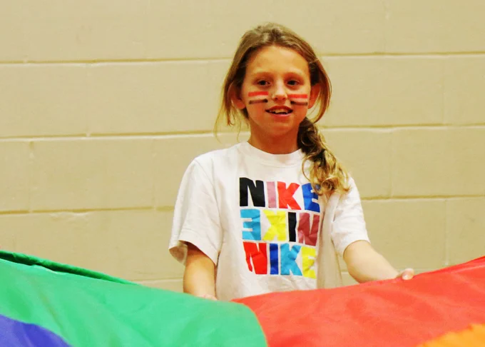 A Rockwood student smiles as she participates in a parachute activity in PE.