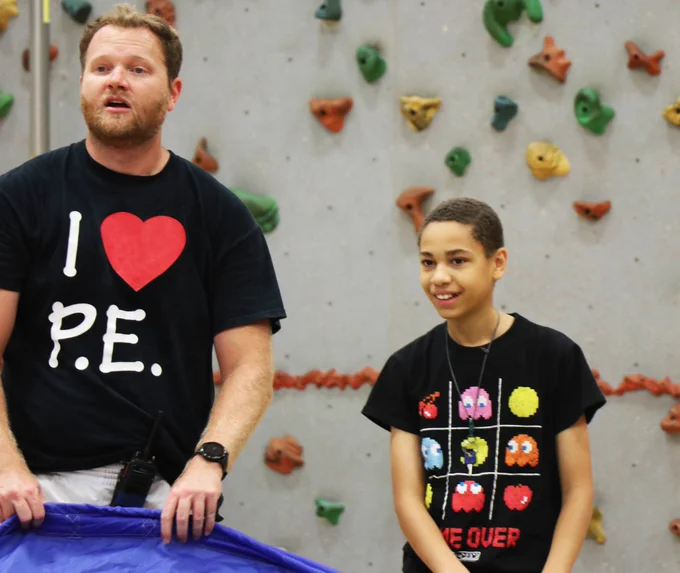 A Rockwood student smiles as his teacher prepares to lead the class through an activity in PE.