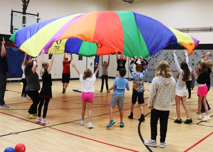Rockwood students and educators release a parachute and it billows into the air during PE.