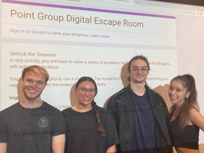 Photo of four students in front of a projector screen (Team 2)