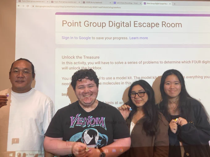 Photo of four students in front of a projector screen (Mystery Team)
