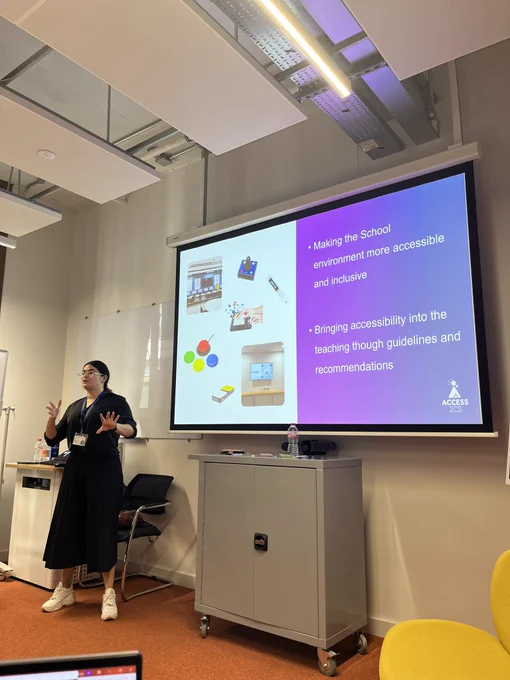 Women at top of a room with screen with a number of assistive technologies and text that says ‘Making the school environment more accessible and inclusive. Bringing accessibility into the teaching through guidelines and recommendations.