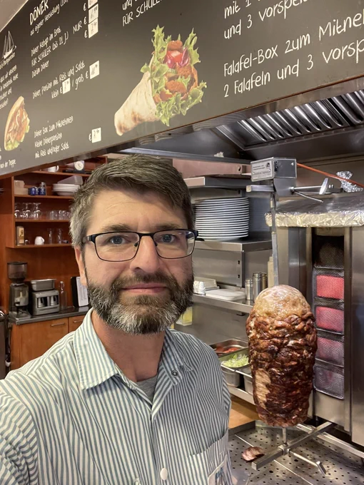 Selfie of the author in a Turkish bistro, with a Döner Kebap grill in the background.