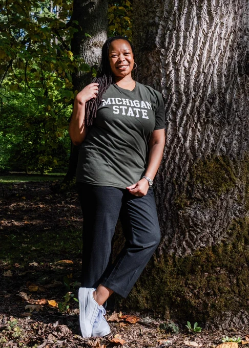 Picture of Thelma Madzima leaning on a tree wearing a Michigan State tshirt