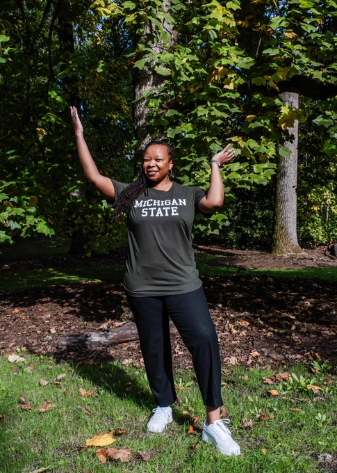 Picture of Thelma wearing a Michigan State tshirt with her hands in the air