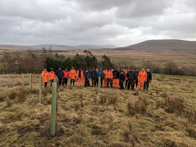 A group of people stand in a hilly landscape. 