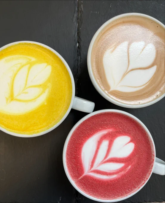 Three different types of latte in white cups with flower motif latte art.