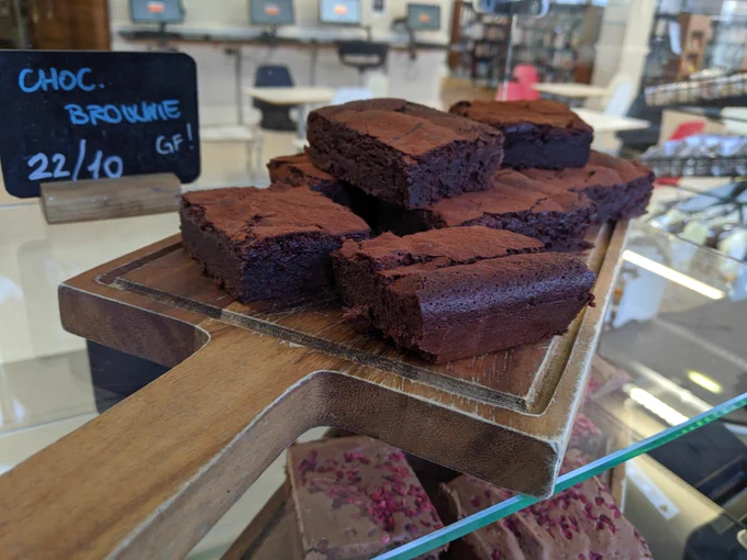 A wooden chopping board holding a pile of chocolate brownies.