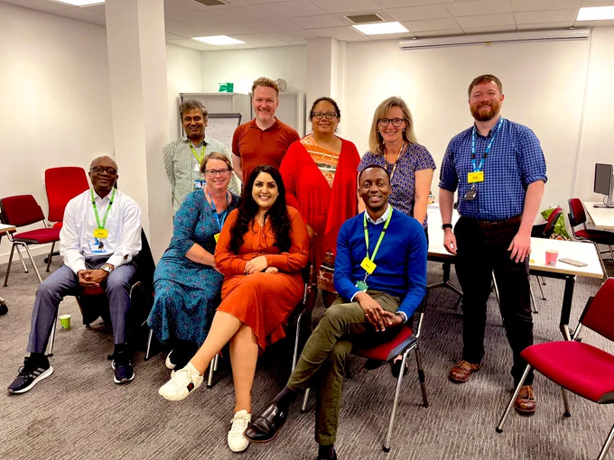 Photo of 9 people in a meeting room, smiling