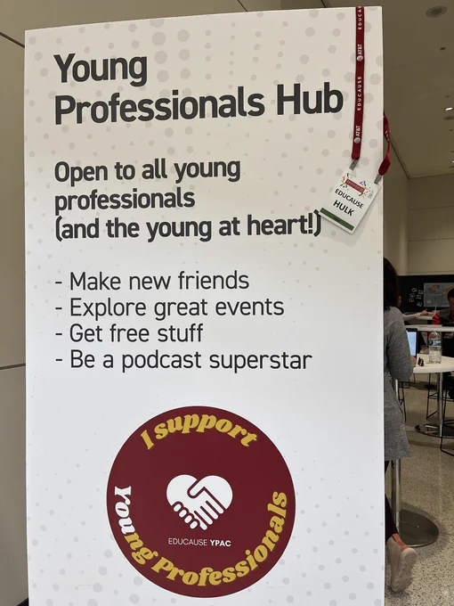 Young professionals sign with an EDUCAUSE HULK badge hanging on it.