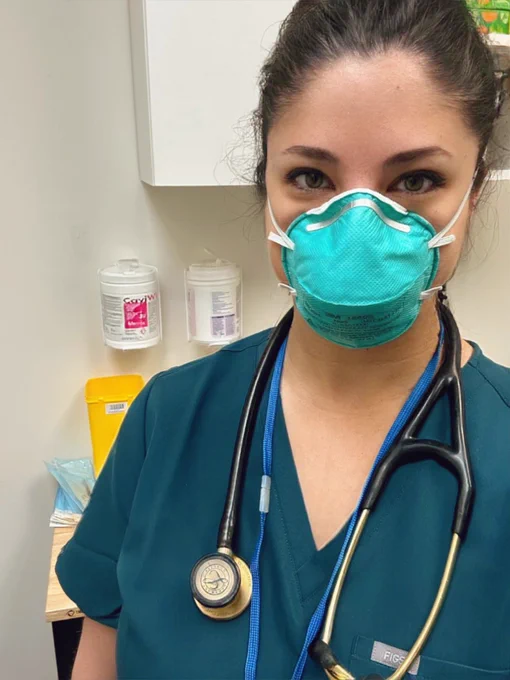 A selfie of me wearing scrubs, a stethoscope and an N95 mask in a medical clinic