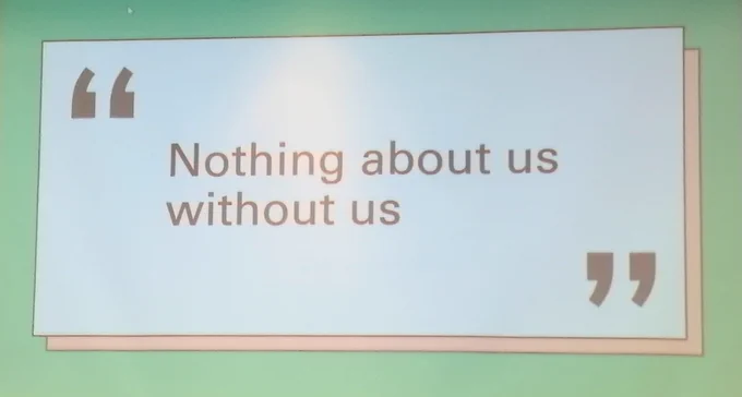 Screen with projected text that reads "Nothing about us without us".