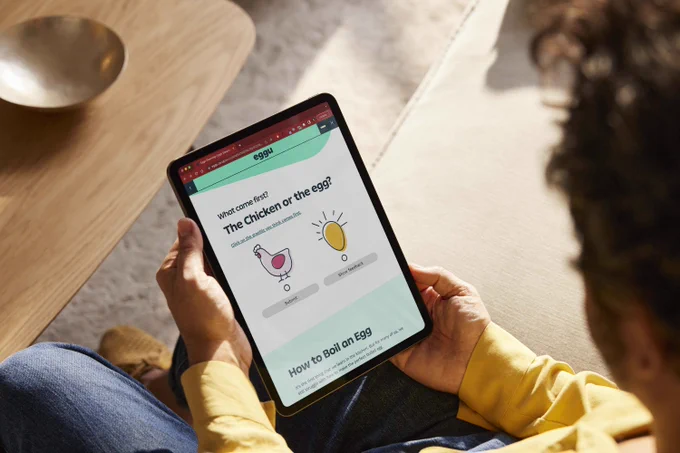 A man is holding an ipad with Eggu digital learning on the screen.