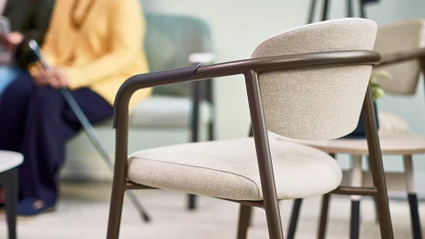 The Steelcase Health Radia guest chair in a light brown upholstery with darker brown metal arms and legs.
