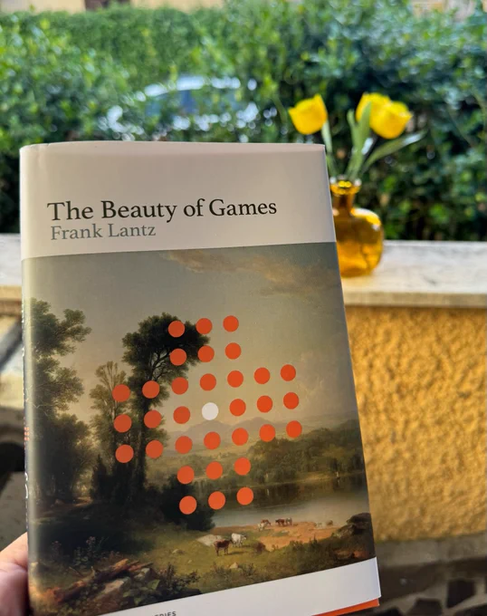 A picture of the book The beauty of games, by Frank Lantz, taken in my garden