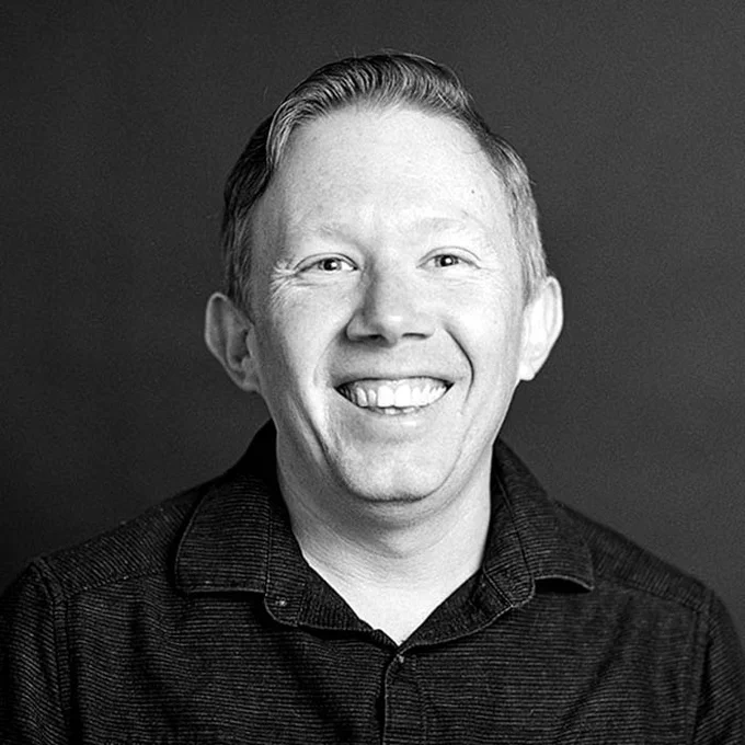 Kevin Zollman is smiling and wearing a collared shirt. The image is in black and white.
