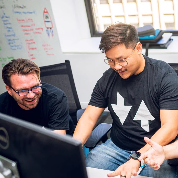 Two men learn coding while working together on a computer.