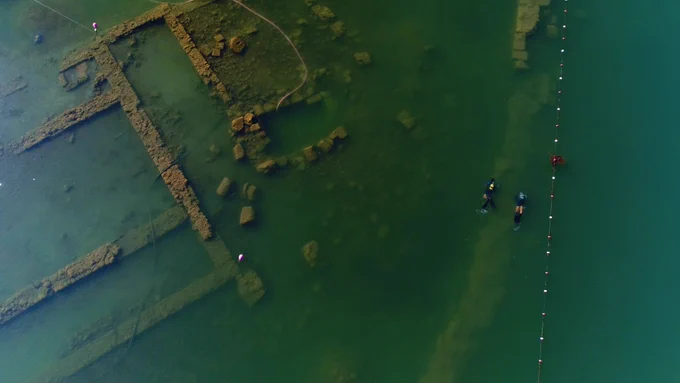 The outline of a large stone building is visible through blue-green water. 