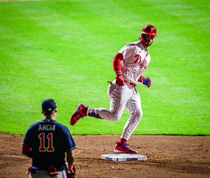 Photo of Bryce Harper staring doing Orlando Arcia while stepping on second base after hitting his second home run of the game. He's wearing the red pinstripes Phillies uniform.