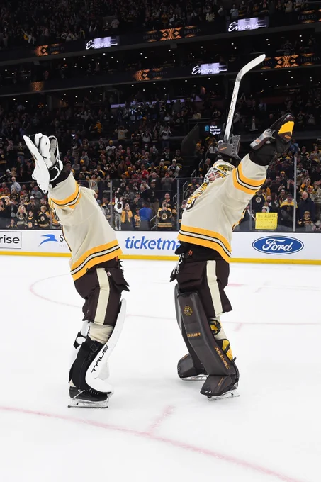 Jeremy Swayman and Linus Ullmark throw their hands in the air as they hug after the B's Opening Night win.