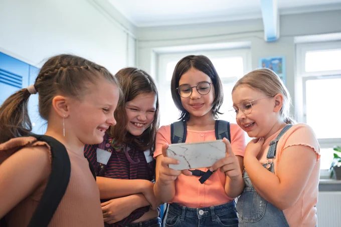 Alt text: School girls using a smart phone together
