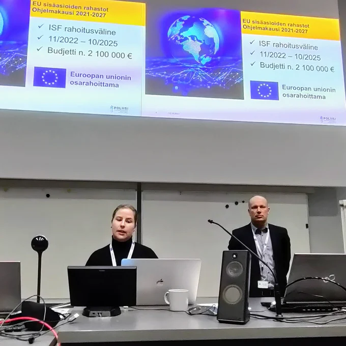 Noora Järvensivu ja Tero Toiviainen esittelevät kyberhankkeita auditorion edessä. Kuvassa näkyy myös sivu PowerPoint-esityksestä.
