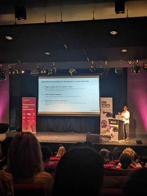 April on stage at Interact London, text on screen explained in tweet