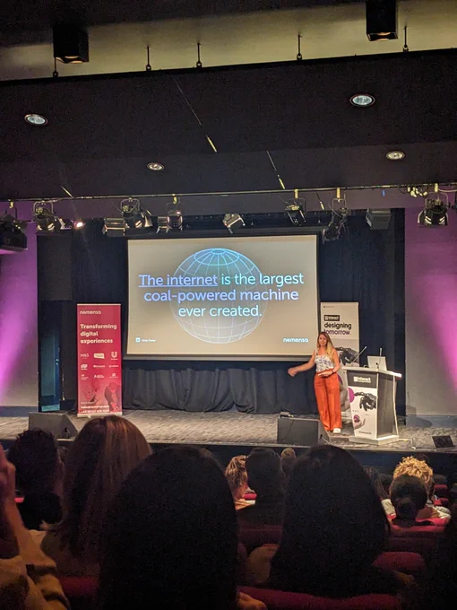 Emily on stage at Interact London. Text on screen given in tweet 