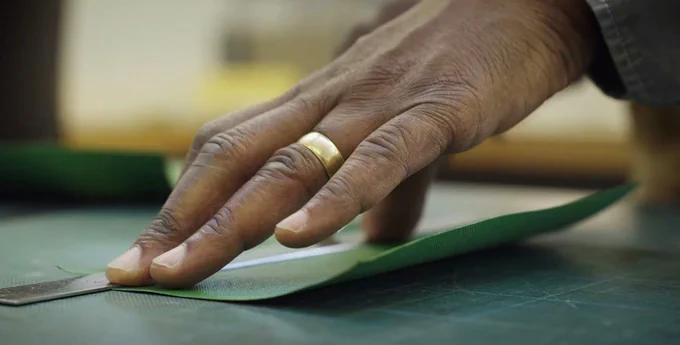 A close up of Roger's hand, using a ruler to line up a piece of paper.