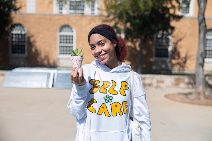woman with succulent and self care sweater