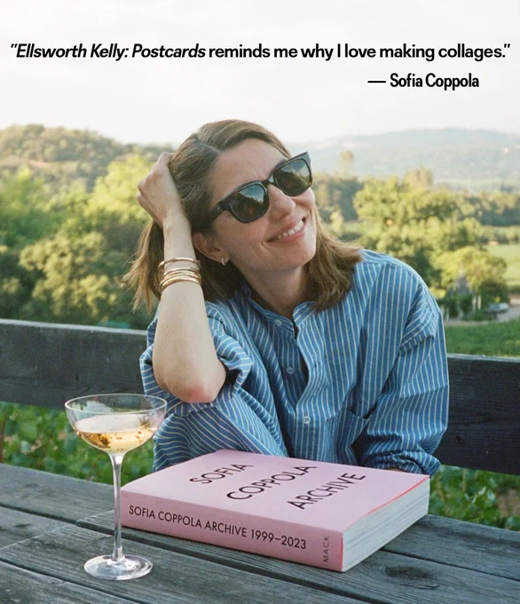 A woman sits before a book and a martini glass.