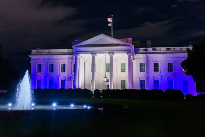 The White House is illuminated with blue and white lights.