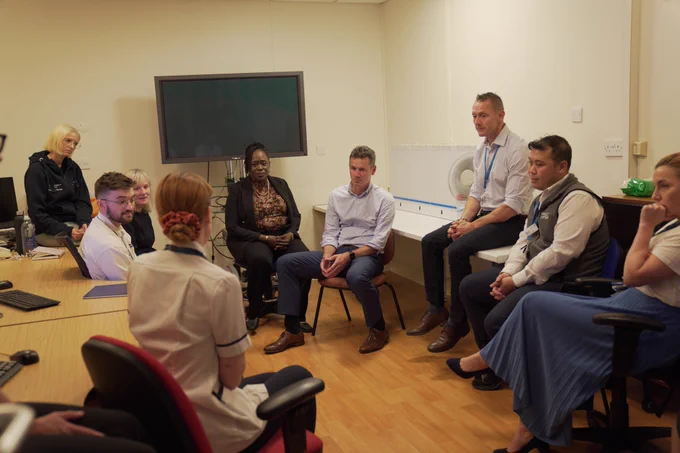 Image shows a group of NHS England and Imperial College Healthcare staff seated around tables and having a discussion.