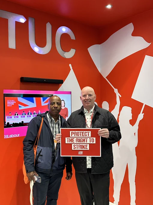 Julian and Tony in front of the TUC stall back drop, holding a ‘Protect the Right to Strike’ placard.