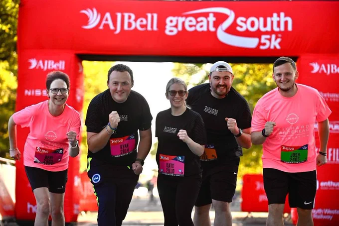A group of runners near the start line pose for a phot