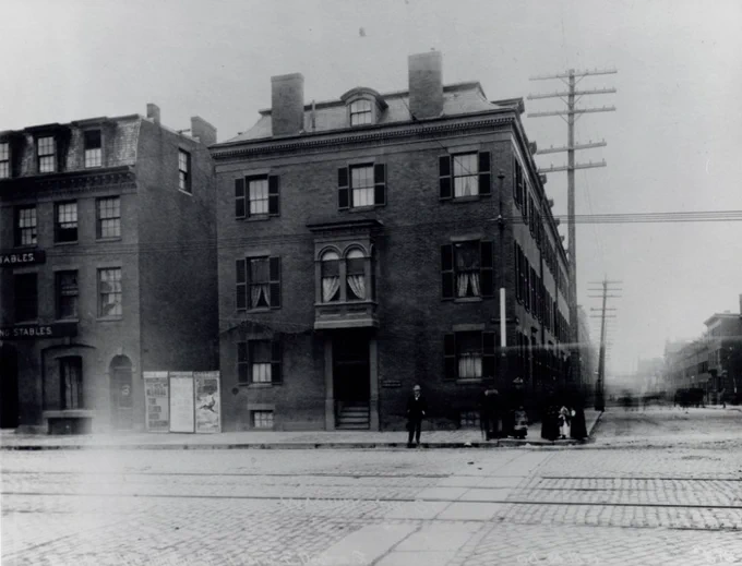 Street scene with cobblestone street, brick buildings, and trolley tracks