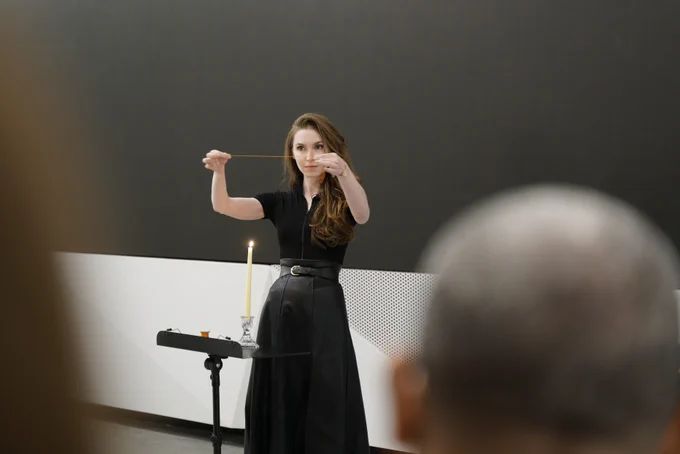Magician Jeanette Andrews holds a length of red thread above a burning candle. 