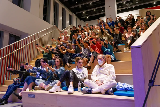 Members of the audience at the MIT Museum  hold a black card in front of them as part of an optical experiment. 
