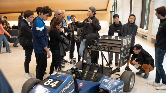 A group of individuals gather around a sports car inside the Myhal Centre. 