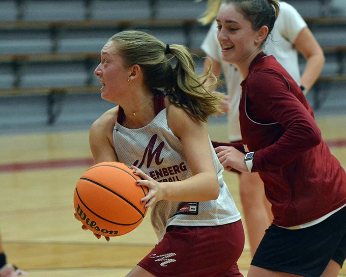 women's basketball player in white jersey dribbling