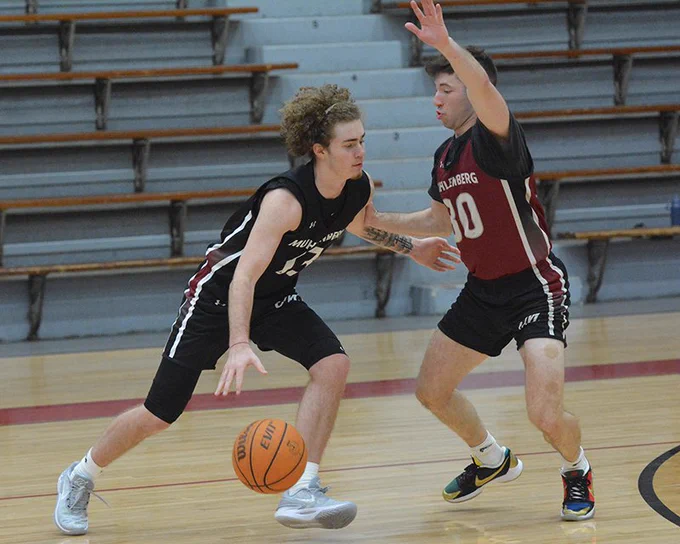 men's basketball player in black jersey guarded by player in red jersey 
