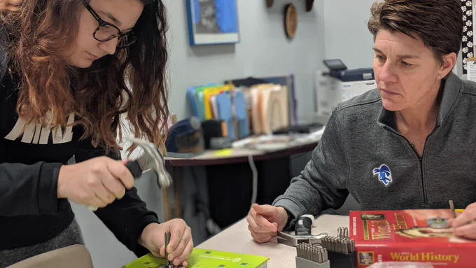 Teacher and student working with hammer