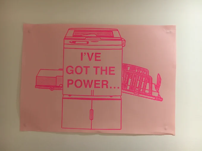 Risographic print of a risograph printer stuck to a wall, with the words I've got the power.