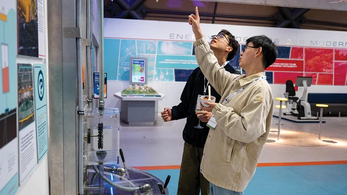 Two ECOC 2023 delegates examine an exhibit at the Glasgow Science Centre during the welcome reception.
