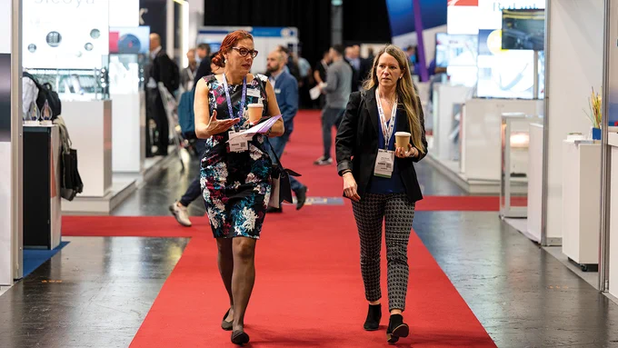 Two women walk through the ECOC 2023 exhibition