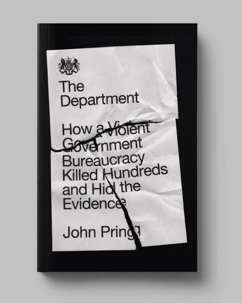 The UK Government coat of arms, featuring a lion, a unicorn and a crown, sits above the following words: ‘The Department. How a violent bureaucracy killed hundreds and hid the evidence. John Pring.’ It is written on white paper against a black background, but the paper is crinkled and at a slant and has been torn in three.