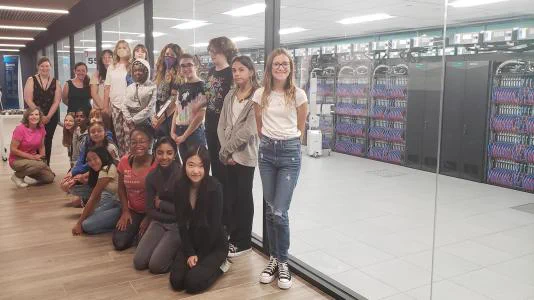 Group of teenage girls clustered in front of the windows next to the supercomputers