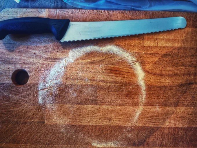 Bread board and knife. Outline of a loaf from the flour, but no loaf. 